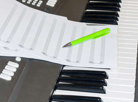 Sheet music and pencil lying on the piano keys. The beginning of the creation of music.の写真素材