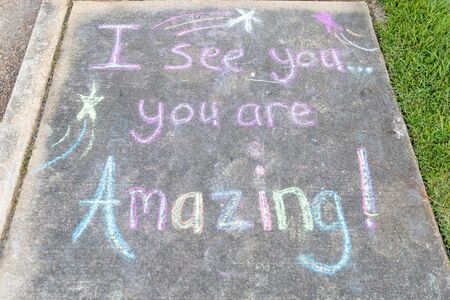 the words "I See You, You are Amazing" written with sidewalk chalk on gray concrete pavement backgroundの写真素材