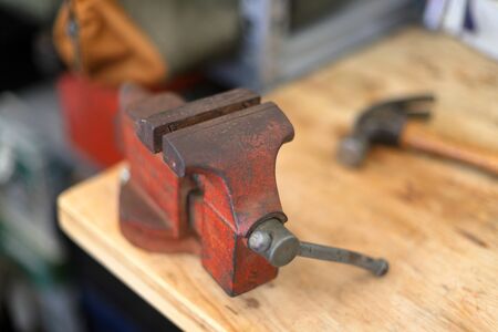 Vintage old red vise on wooden workbench with tools and hammerの写真素材