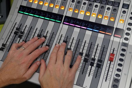 Hands mixing audio on Digital Sound mixing console