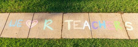 The words "We Love Our Teachers" written with sidewalk chalk, on gray concrete pavement background.の写真素材