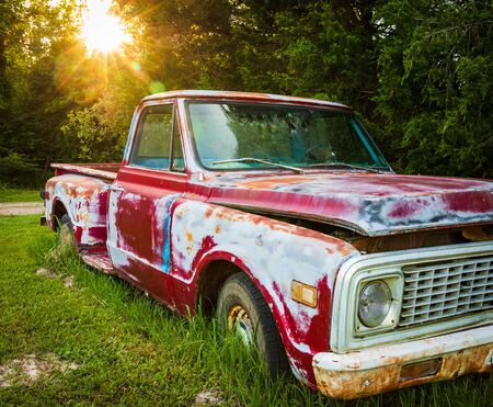 Antique red truck parked in a field on a farmの写真素材