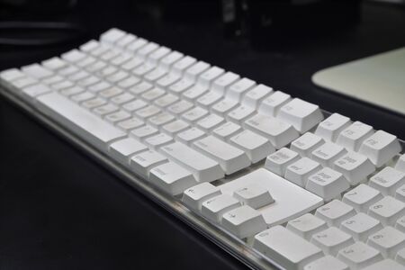 White computer keyboard on black desk used for data entryの写真素材