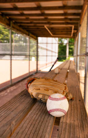 Baseball and glove on dugout bench with blurred backgroundの写真素材