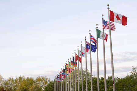 Several National flags waving on top of flag poles off center