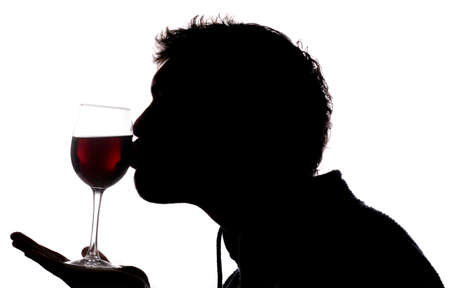 Man kissing glass of red wine silhouetteの写真素材