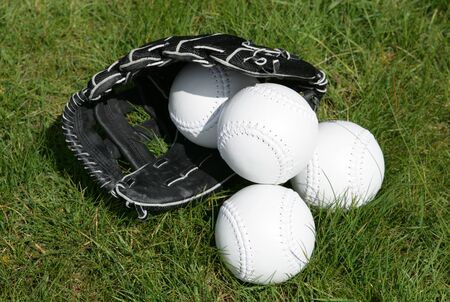 softball glove and balls on grassの写真素材