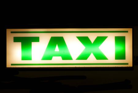 Neon green taxi sign at nightの写真素材