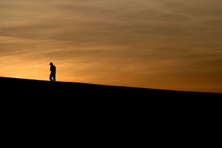 A distraught boy walks off toward the sun.の写真素材
