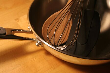 Several cooking tools sitting in a frying pan.