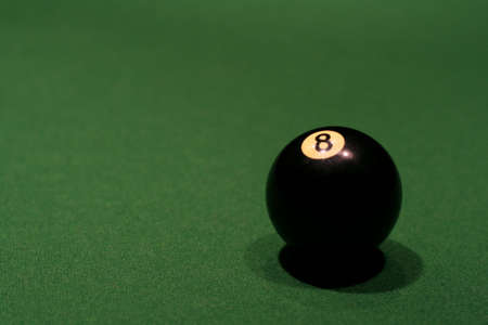 A eight ball sitting on a pool table.