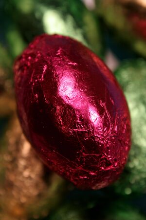 A closeup of a red foil Easter egg amongst a pile of others.