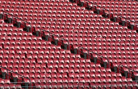 Red stadium seats cast in bright sunshine.