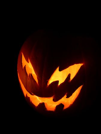 A spooky pumpkin face glowing on Halloween night.の写真素材