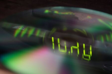 A closeup of dvd with the lights from a digital display reflecting on them.  Note the focus is on the digits.の写真素材