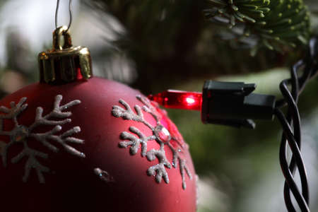 A red snowflake Christmas bauble right next to a red light.の写真素材