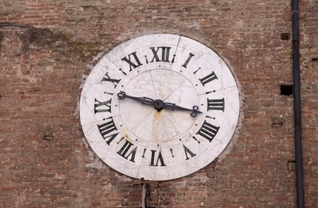 A medieval clock set in a brick wall.  Shot in Siena, Italy.の写真素材