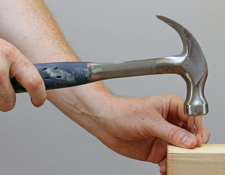 A person hammering a nail into a piece of wood.の写真素材