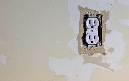 A dirty electrical outlet exposed during a renovation and the surrounding dry wall. の写真素材