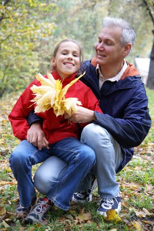 Cheerful father and daughter talking in autumn parkの写真素材
