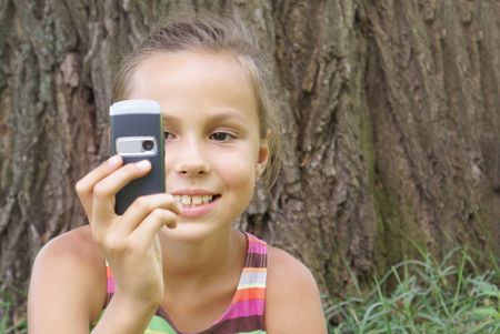 Smiling preteen girl dialing on cell phoneの写真素材
