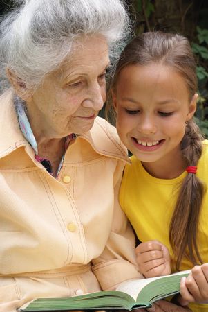 Granddaughter and her grandmother together reading a book                