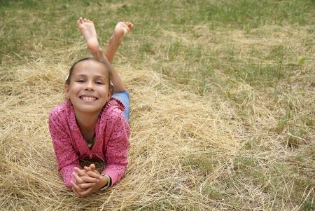 Smiling preteen girl resting on grass               の写真素材