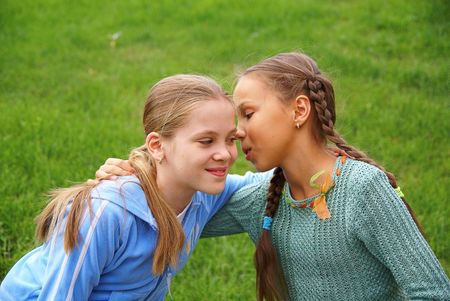 Smiling preteen girls talking outdoors on green grass background             の写真素材