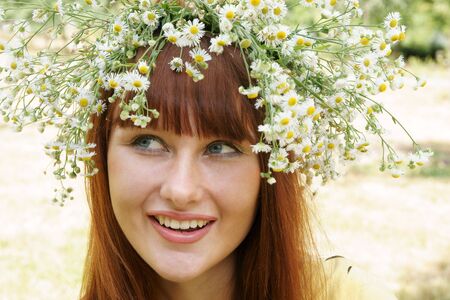 Beautiful young woman in field flower garland outdoorsの写真素材