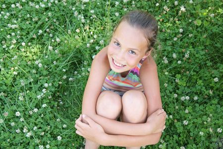 Cheerful preteen girl on clover background outdorsの写真素材