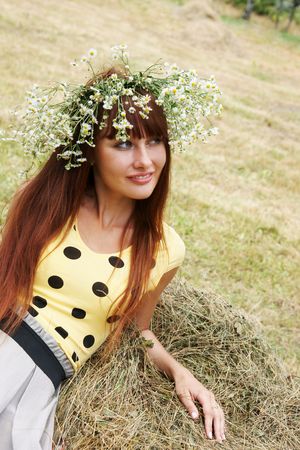 Beautiful cheerful girl in field flower garland outdoors の写真素材