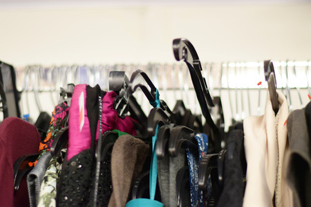 Women's shirts and dresses hanging from clothes hangers for sale on a clothing rack in a store
