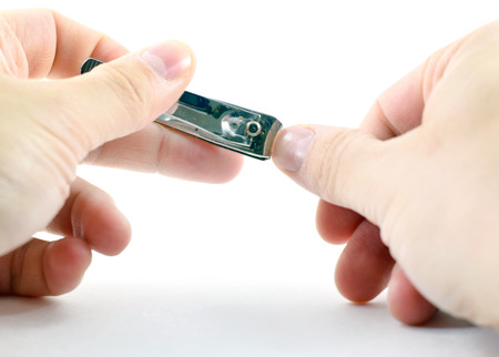 Mail hand holding and using nail clippers - isolatedの写真素材