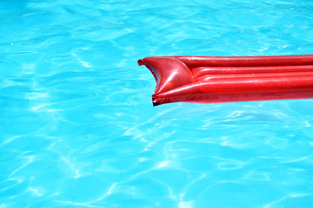 Red inflatable pool raft floating in pool on sunny summer dayの写真素材