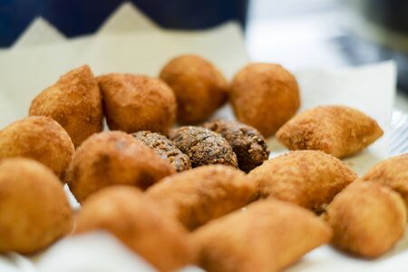 Deep fried Brazilian croquettes draining on a paper towel (coxinha, kibbe, risole)