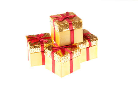 Four small gold boxes with red ribbons on a white backgroundの写真素材