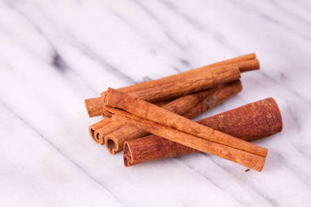 A pile of cinnamon sticks on a marble background