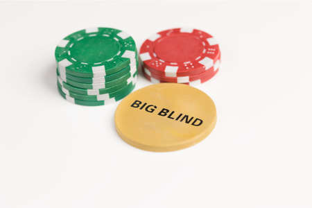 Two small piles of gaming chips behind the big blind token isolated against a white backgroundの写真素材