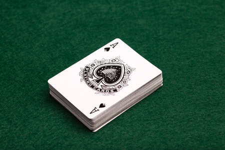 A deck of playing-cards face up on a green baize background with the ace of spades uppermost