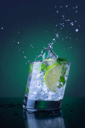 Fresh mojito with splash on a green spot light backgroundの写真素材