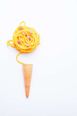 carbonara pasta on a bright white background rolled in the shape of a ball over an ice cream cone shot in plan and verticalの写真素材