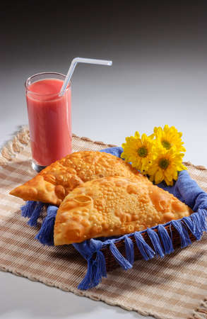Pastries in small basket with blue fabric and glass of fruit juice with plastic straw, decorated...