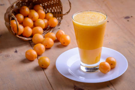 Brazilian fruit caja. Glass of juice on wooden table.