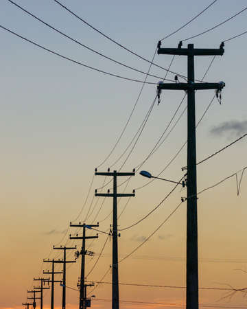 Electrifying posts with orange sunset sky background.の写真素材