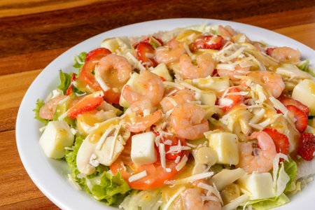 Shrimp and cheese salad on a white plate over wooden table.の写真素材