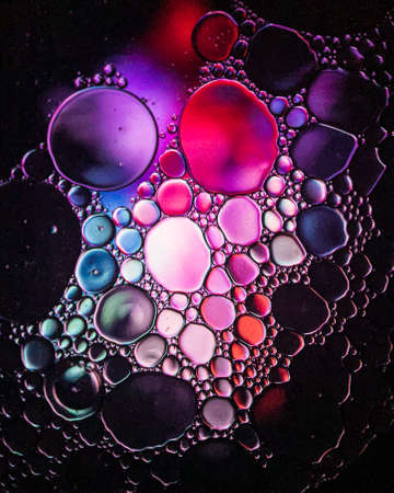 Oil drops on a water surface abstract with a pink and purple background