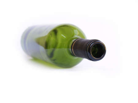 Green wine bottle in soft focus laying down on white background.の写真素材
