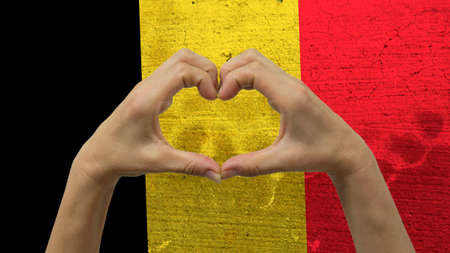 With a stylized Belgian flag background an anonymous person's hands being held in the form of a heart, symbolizing love and patriotism for Belgium.の写真素材