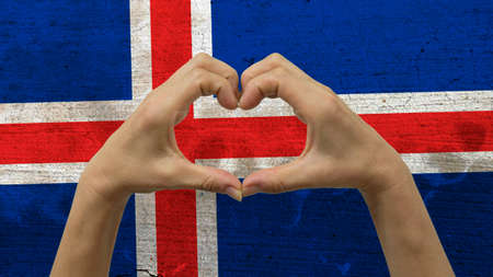 With a stylized Icelandic flag background an anonymous person's hands being held in the form of a heart, symbolizing love and patriotism for Iceland.の写真素材