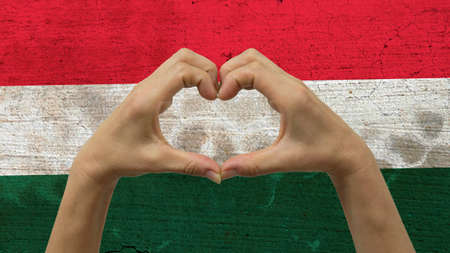With a stylized Hungarian flag background an anonymous person's hands being held in the form of a heart, symbolizing love and patriotism for Hungary.の写真素材